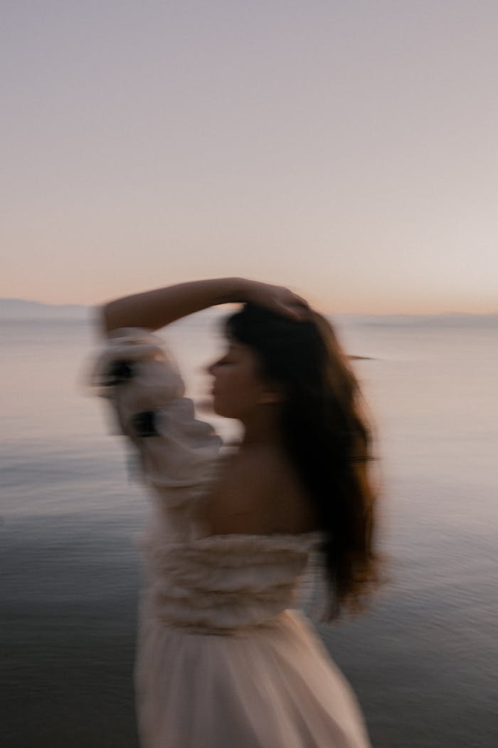 Blurred portrait of a woman by the sea at twilight, evoking mystery and tranquility.